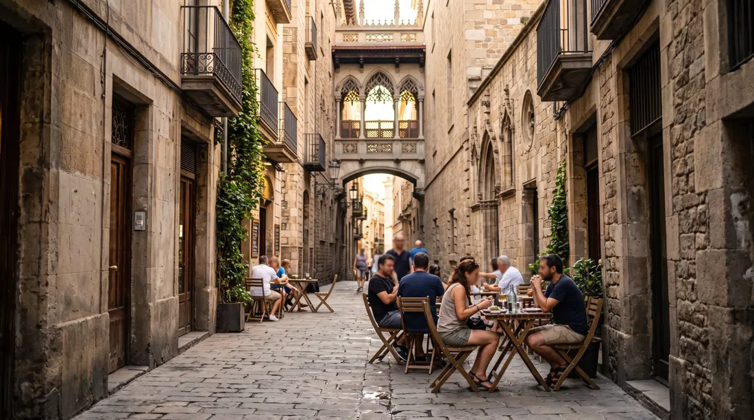 narrow stone lanes of the Gothic Quarter near Carrer del Bisbe, late-afternoon light catching a hidden square and café tables